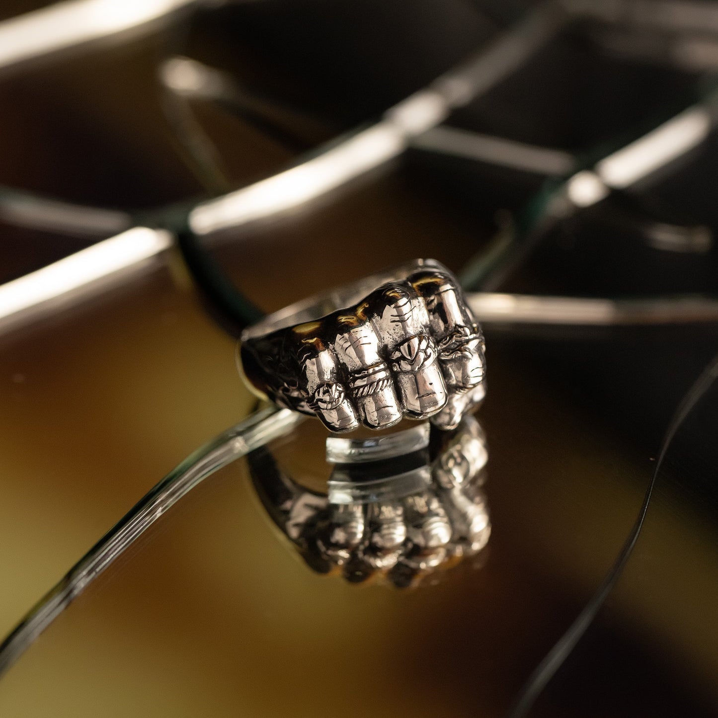 Close-up of a silver ring with intricate design on a reflective surface.