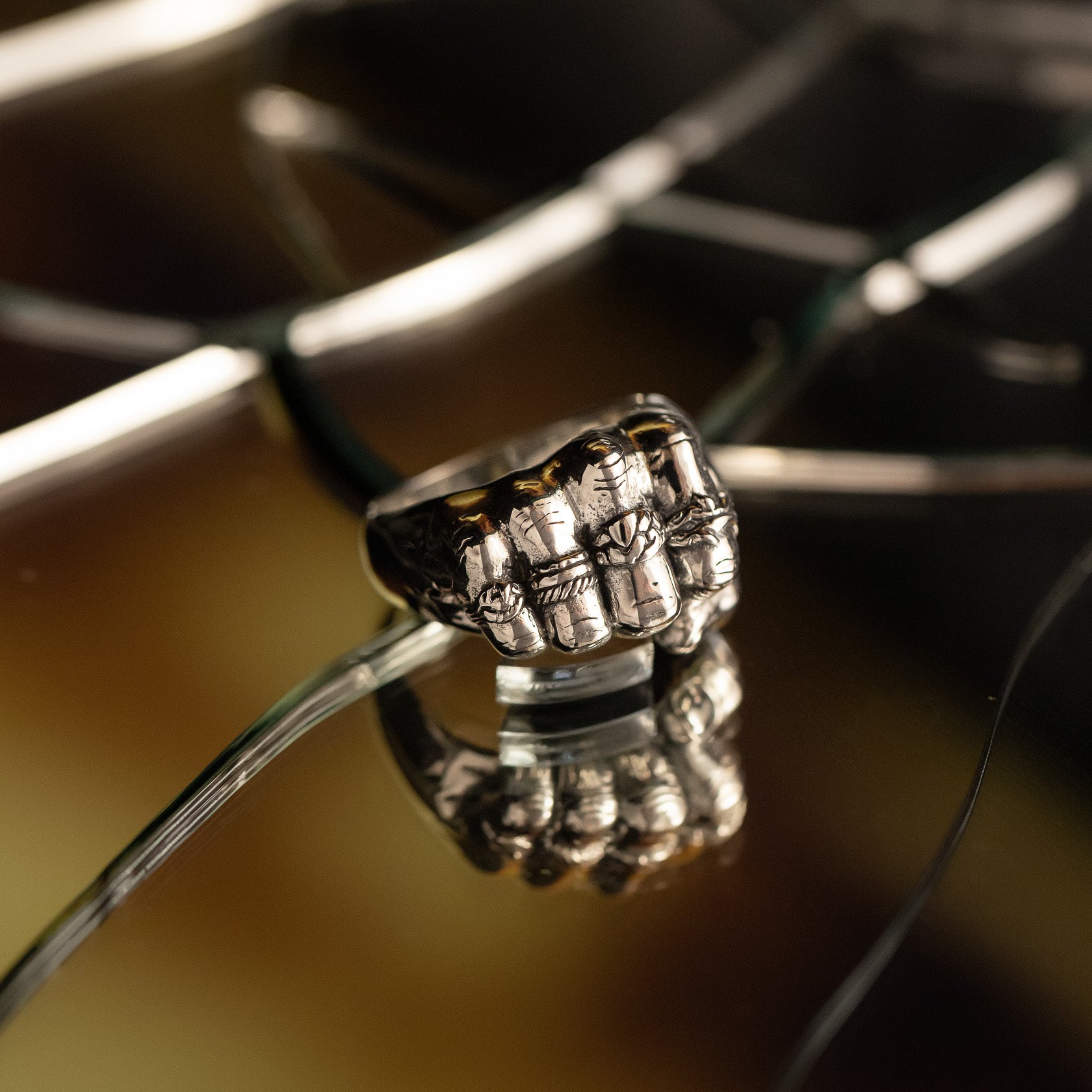 Close-up of a silver ring with intricate design on a reflective surface.